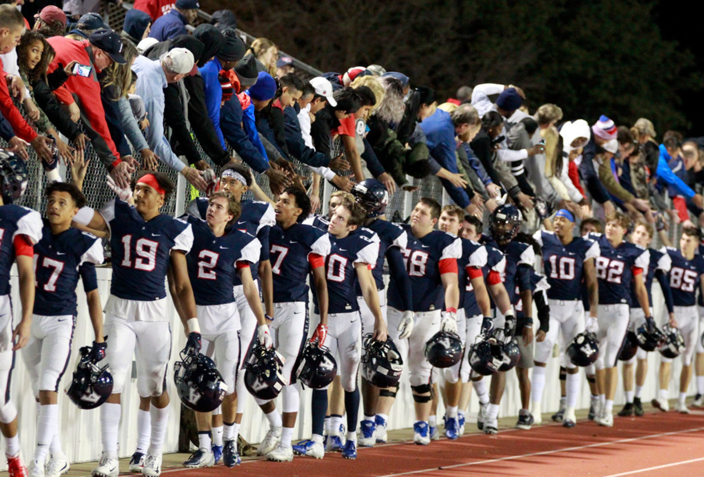 Allen team members slap hands with fans at the end of their 52-40 win over Rockwall in the...