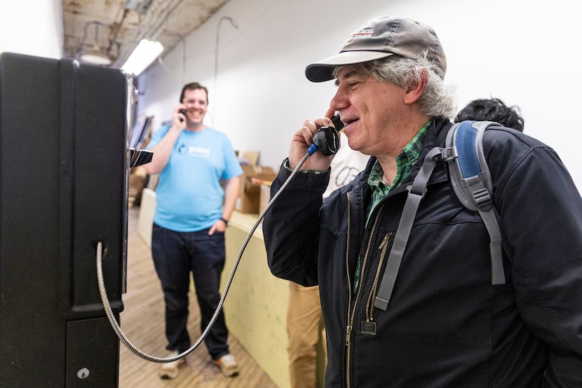 Mark Dank, co-founder of PhilTel (left), calls the newly installed payphone while Bernie...