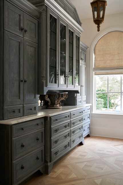 A large wood cabinet with a countertop offers storage in a butler's pantry.