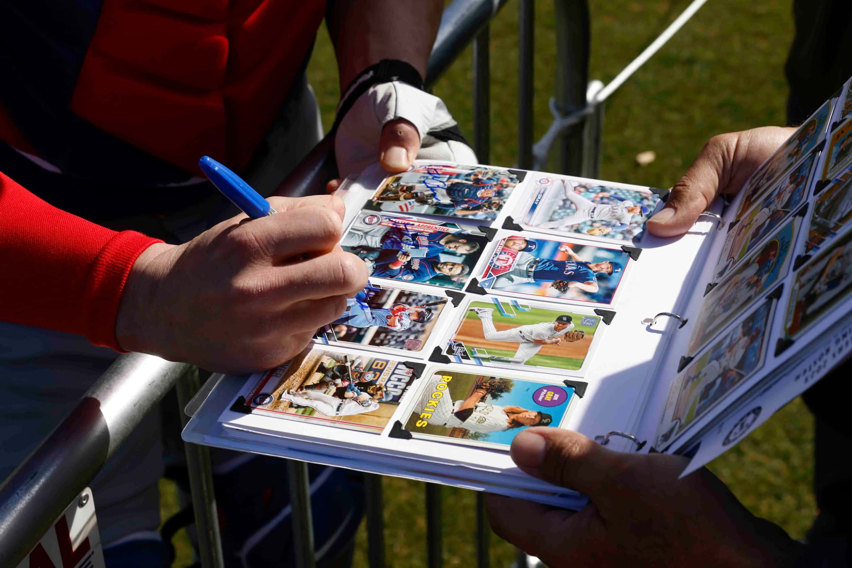 Texas Rangers catcher Mitch Garver gives autograph to fans during a spring training workout...