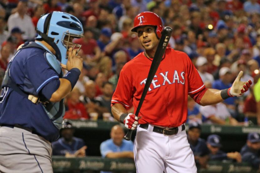 Texas right fielder Alex Rios argues a called strike call by home plate umpire Jeff Kellogg...