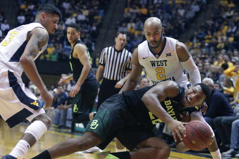Baylor guard King McClure (22) falls while being trapped by West Virginia guard James Bolden...