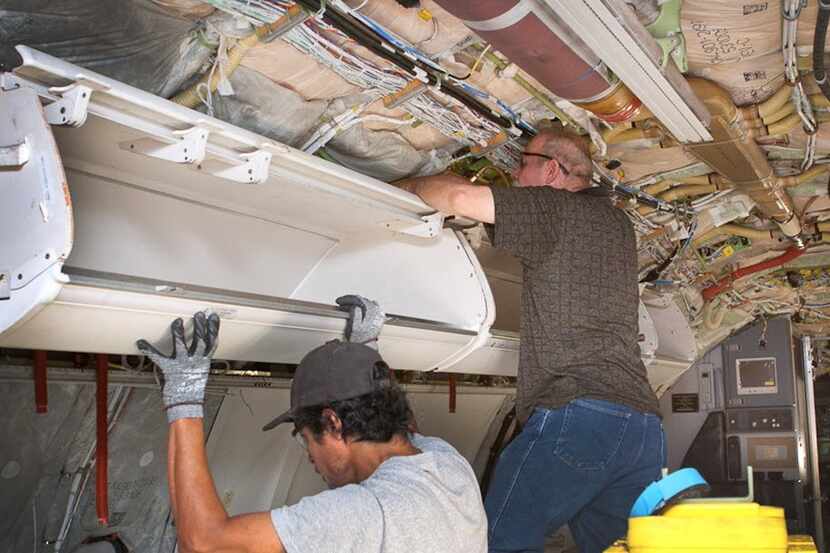  American Airlines workers install larger carry-on baggage bins on a Boeing 737 jet, in...