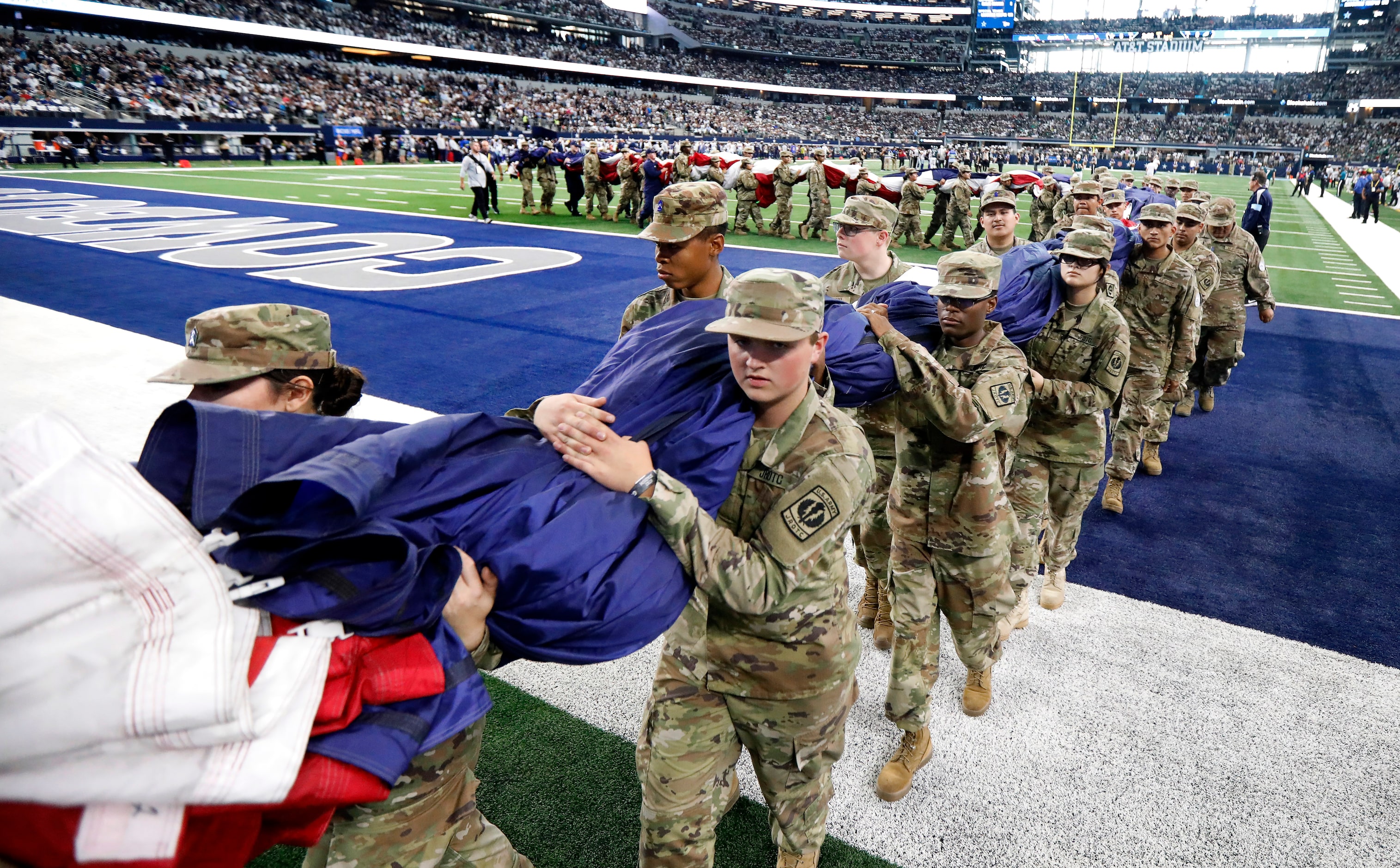 Army Jr ROTC members carry a field-size U.S. flag off the field following the national...