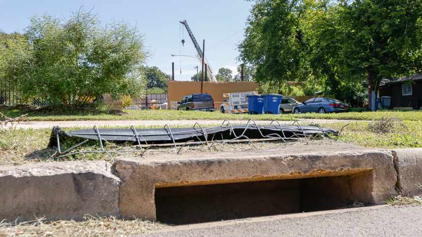 A stormwater drain along Alcalde Street with a cover tossed on top of it near the...
