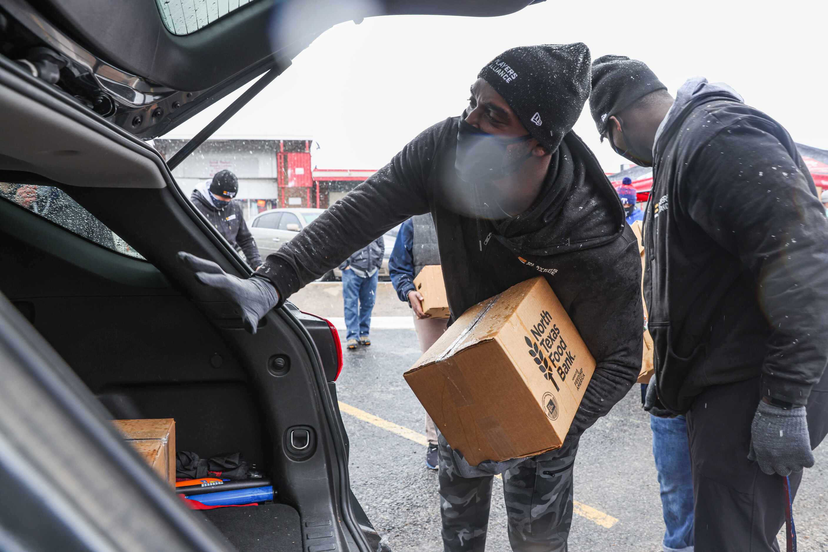Rangers pitcher Taylor Hearn, places a box of food in the truck of a car as part of the...
