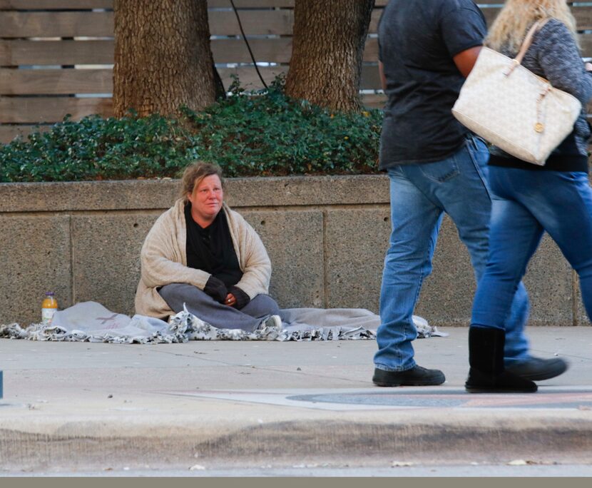 Lisa Kelso watches pedestrians pass her on St. Paul St. at the intersection of Jackson St....