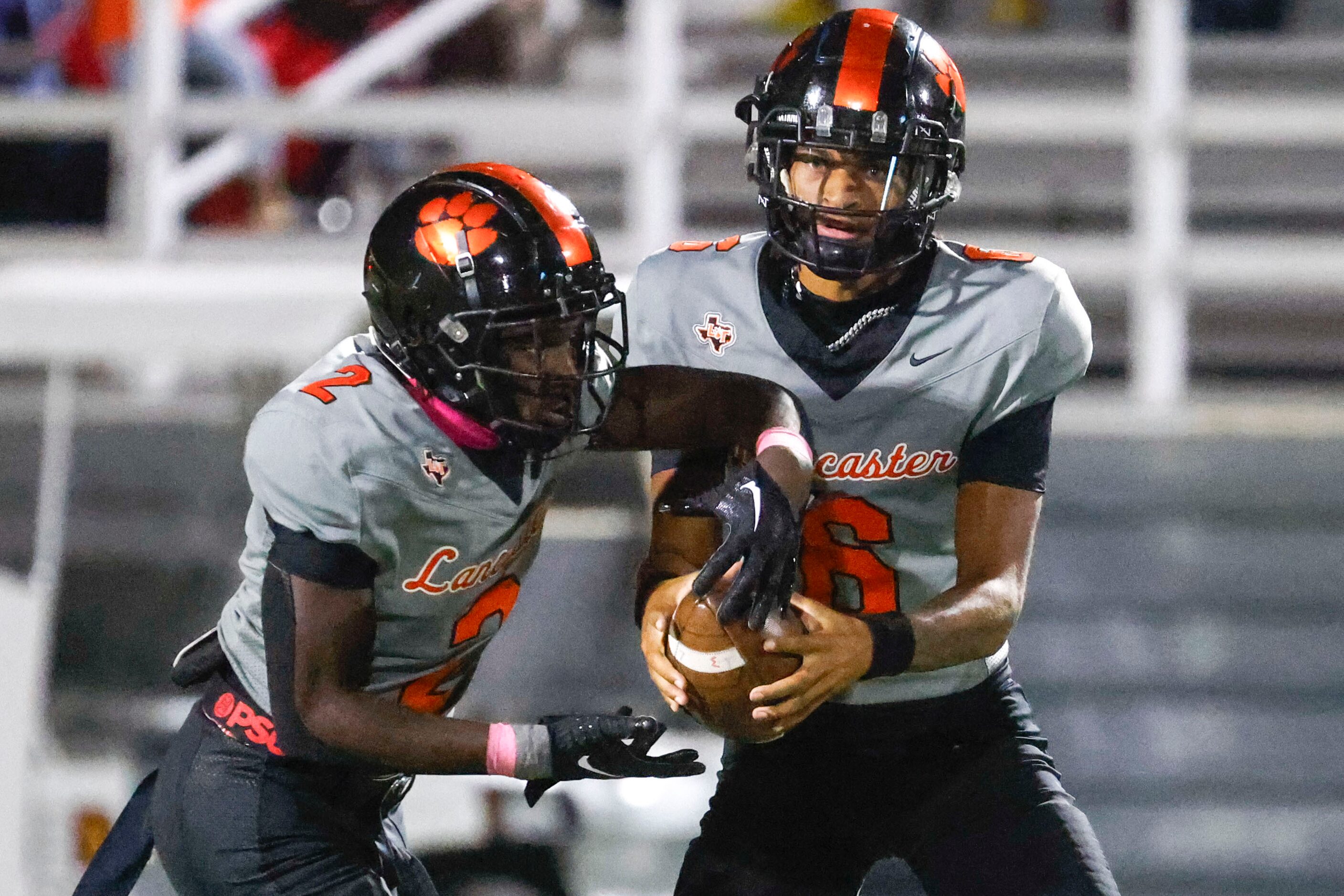 Lancaster High’s Izayah Lee (left) takes the ball from QB Carter Jones during the first half...