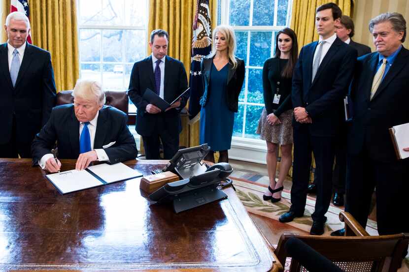 President Donald Trump signs an executive order Wednesday in the Oval Office of the White...