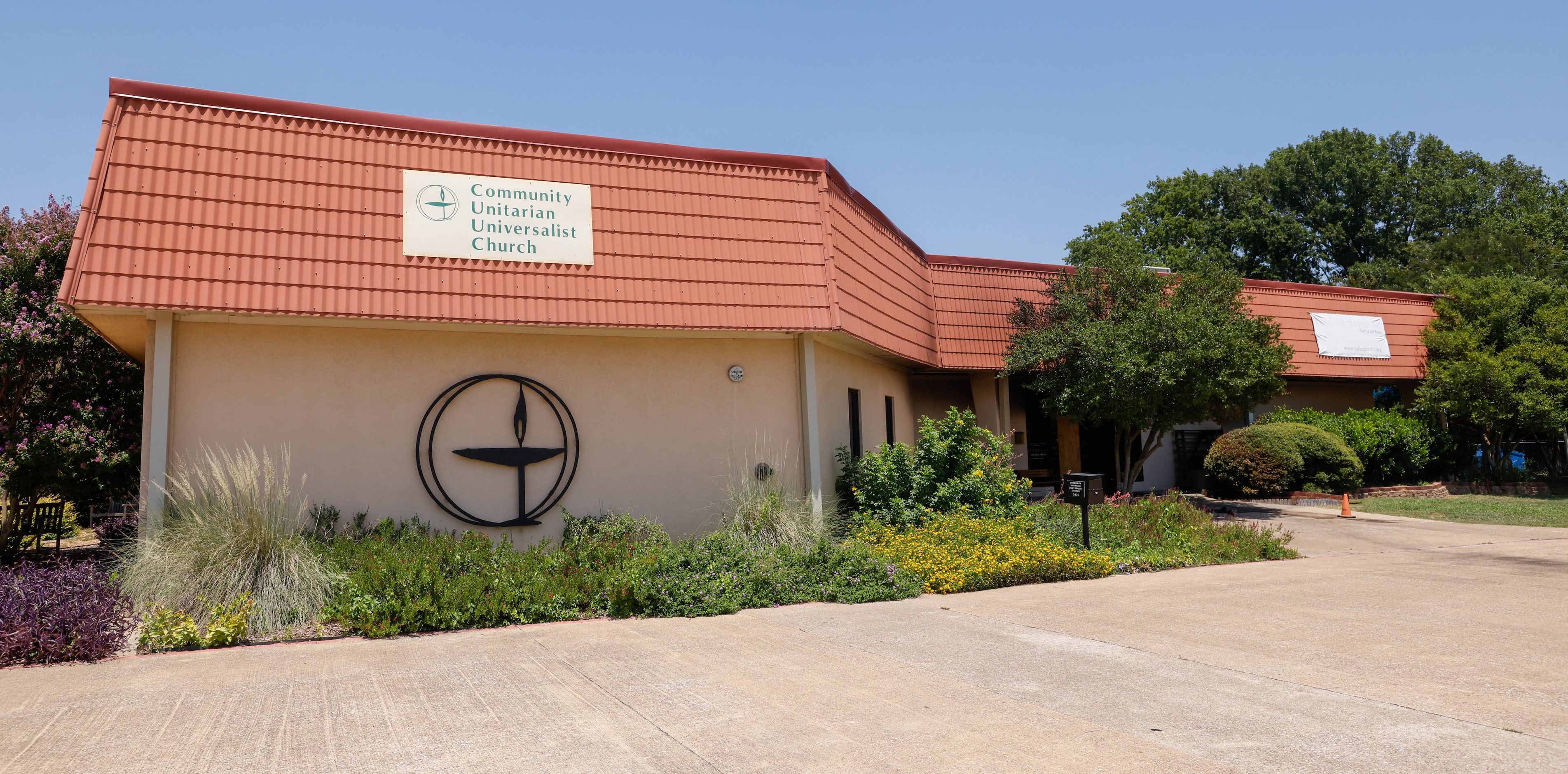 A sign for the Community Unitarian Universalist Church of Plano hangs from the left side of...