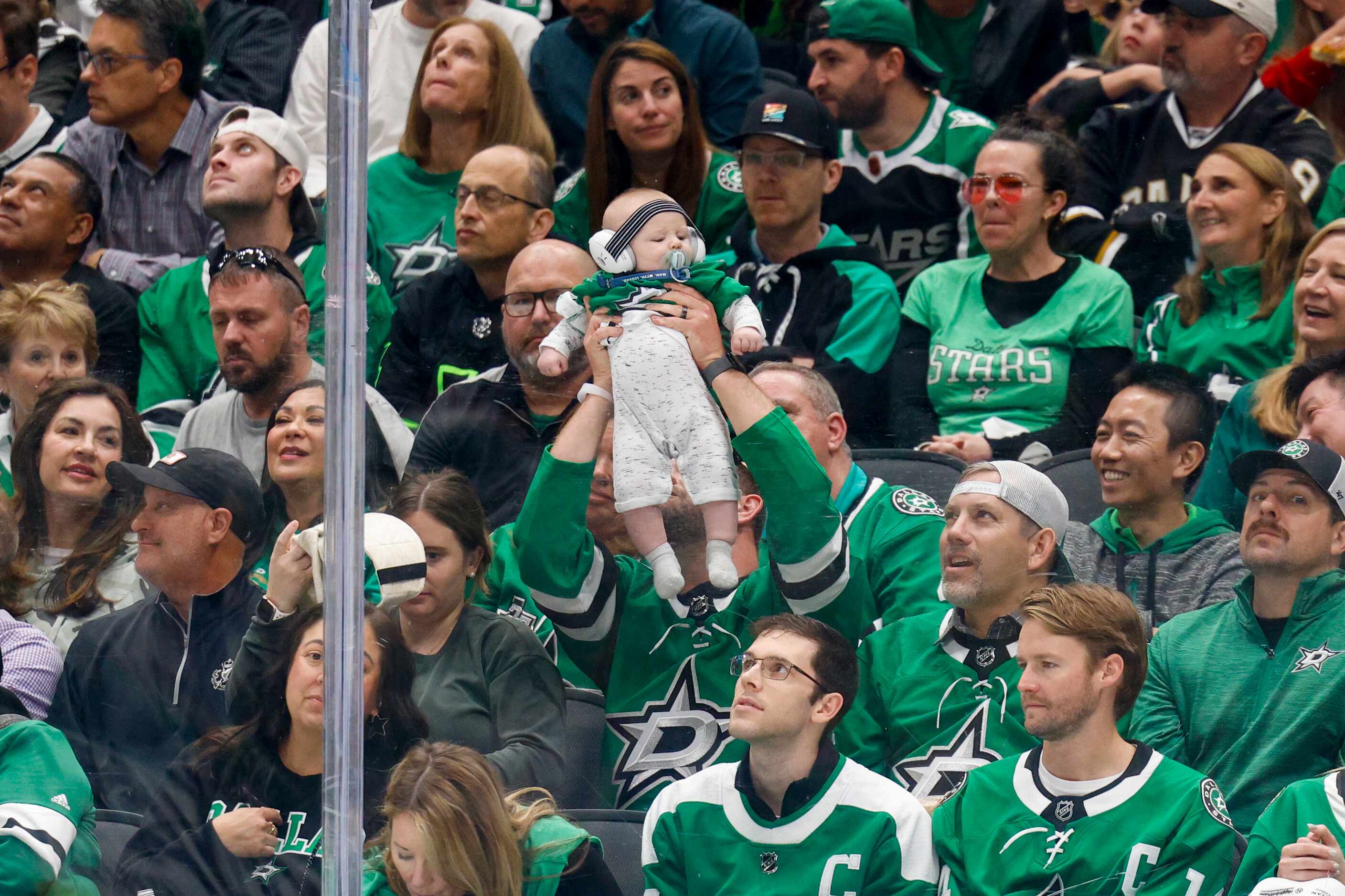 A fan raises their baby during a timeout during the second period of Game 5 of an NHL hockey...