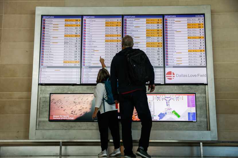 Travelers walk in front of the Departures board at Dallas Love Field airport in Dallas on...