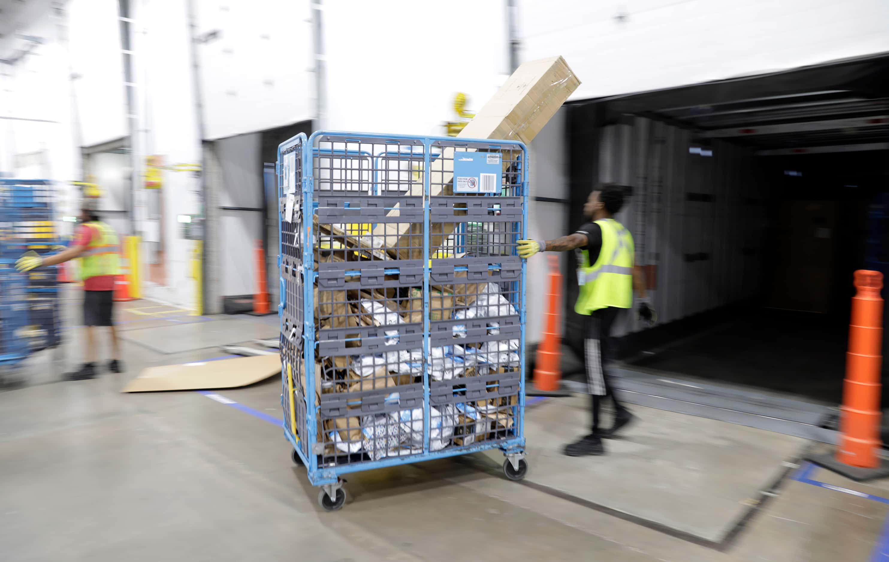 A crew member unloads a semi-truck full of early PRIME day deal packages as they arrive via...