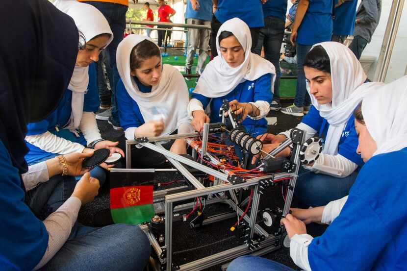 Members of the Afghani all-girls robotics team make adjustments to the team robot in the...