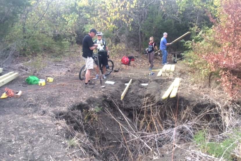 
Volunteers from the Dallas Off Road Bicycle Association work around a sink hole created by...