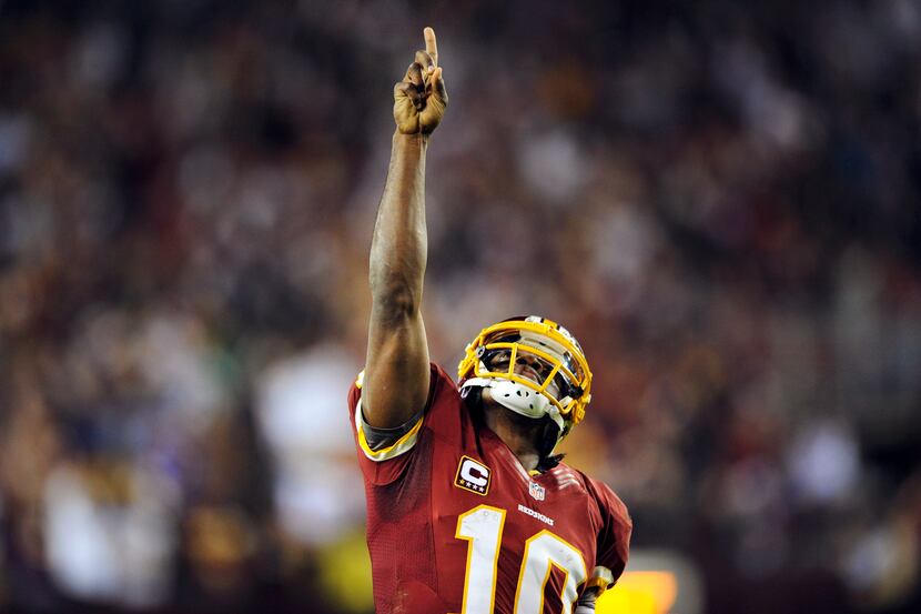 Washington Redskins quarterback Robert Griffin III points skyward after throwing a touchdown...