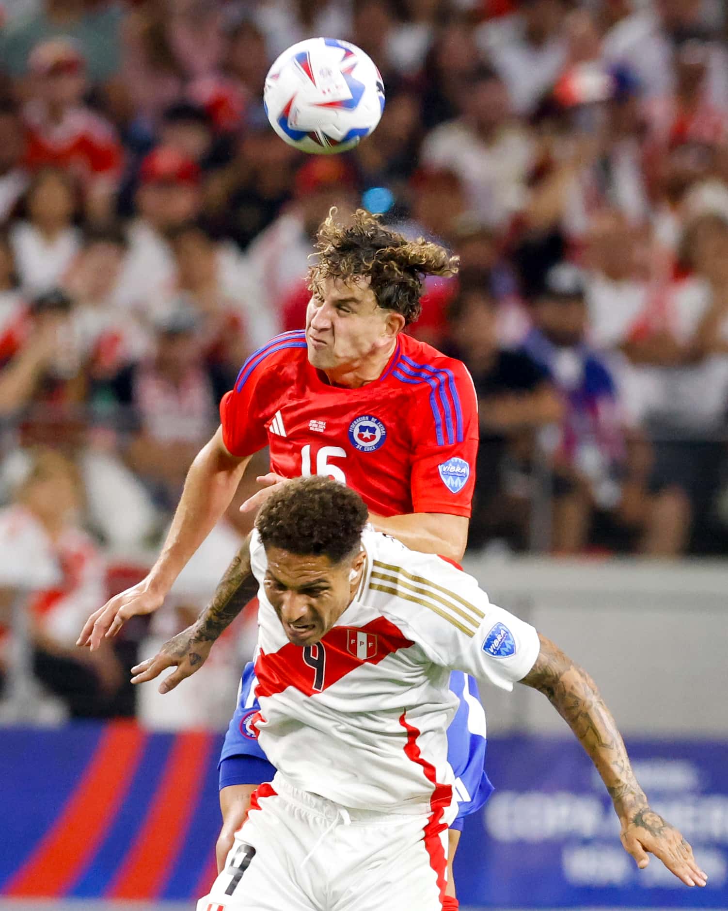 Chile defender Igor Lichnovsky (16) heads the ball over Peru forward José Paolo Guerrero (9)...