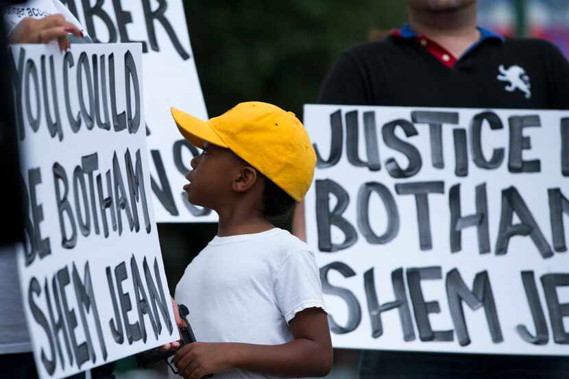 "Young King" Solomon Grayson, 6, looked at a sign that reads "You Could Be Botham Shem Jean"...