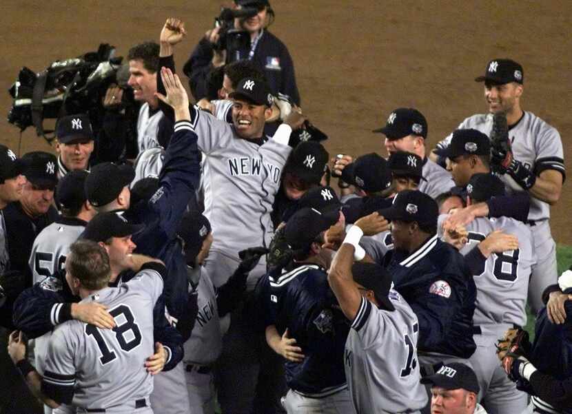 NEW YORK, UNITED STATES:  New York Yankees relief pitcher Mariano Rivera (C) is raised in...