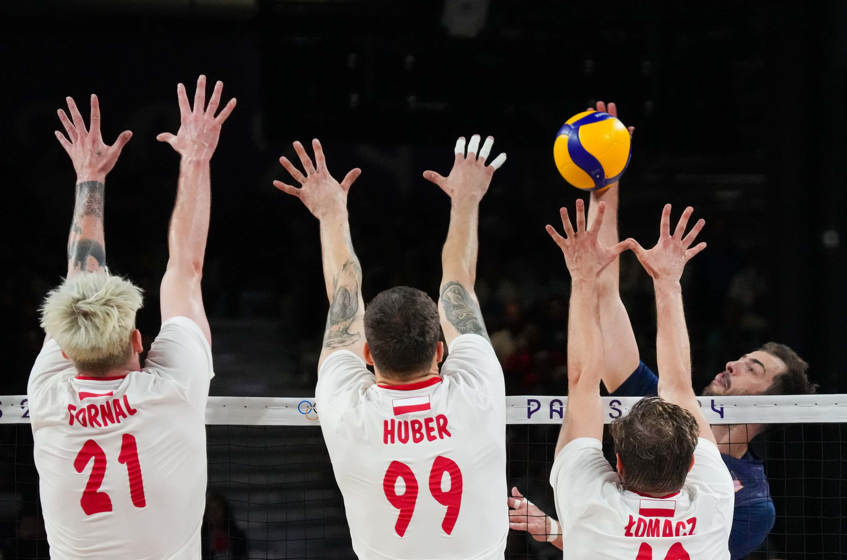 Aaron Russell (2) of the United States tries to hit over the block of Tomasz Fornal (21),...