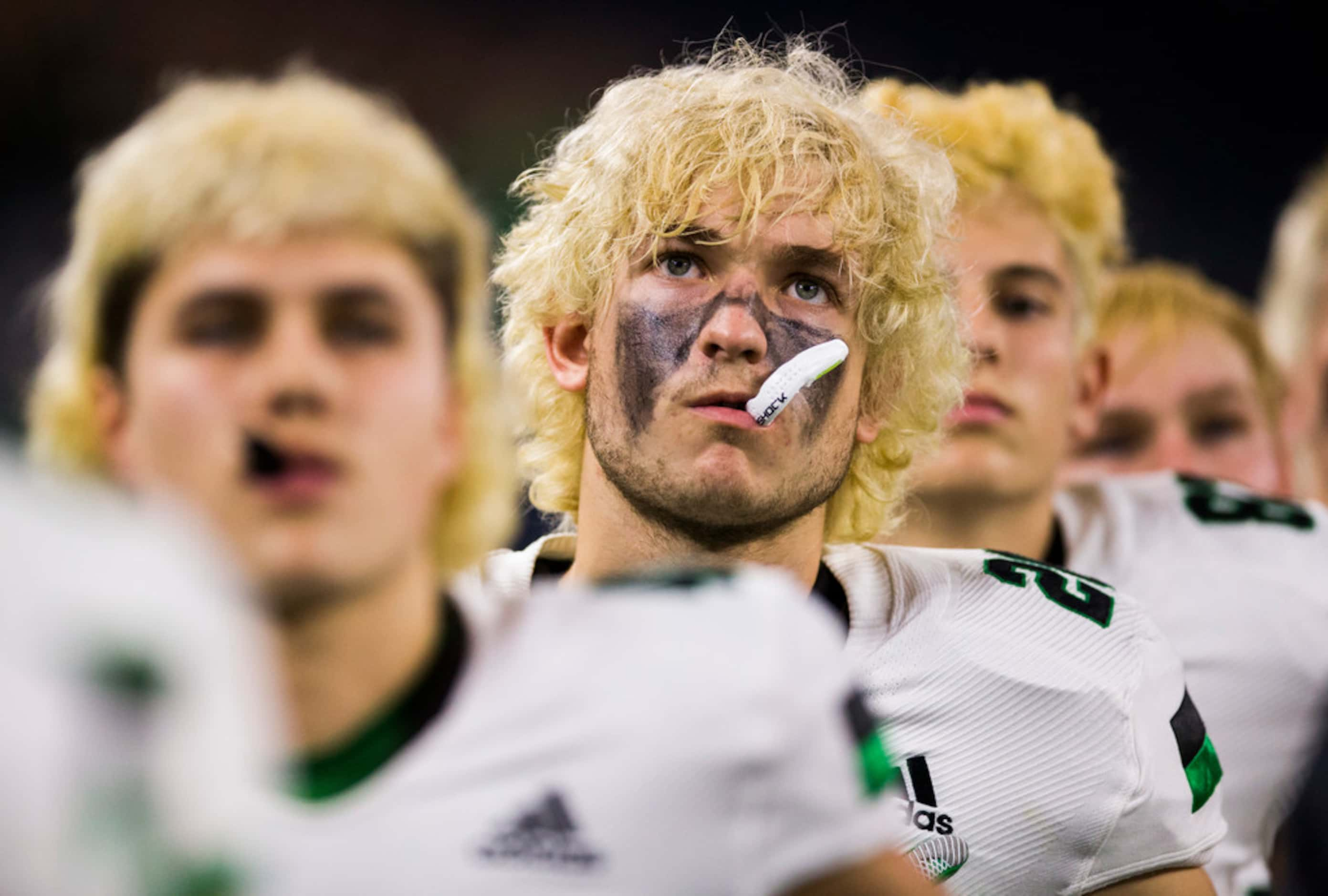 Southlake Carroll football players listen to the national anthem before a Class 6A Division...