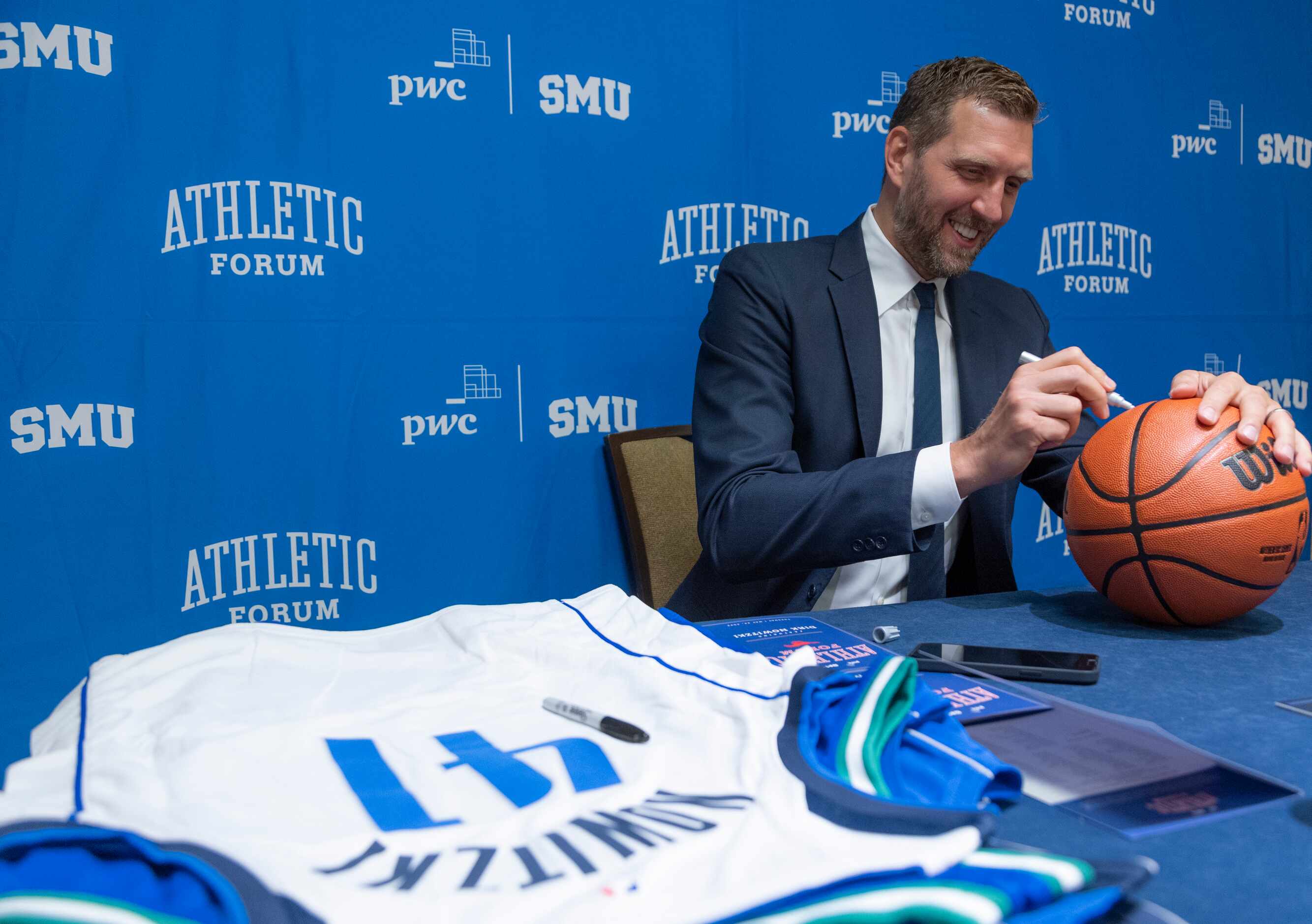 Former Dallas Mavericks player Dirk Nowitzki autographs a basketball before speaking at the...