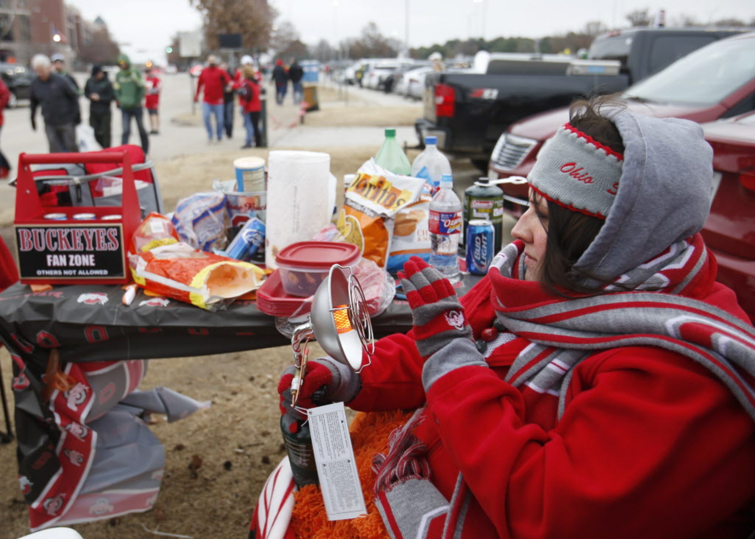 Jamie Satterfield of Grandbury warms up with a portable heater as she tailgates before a...