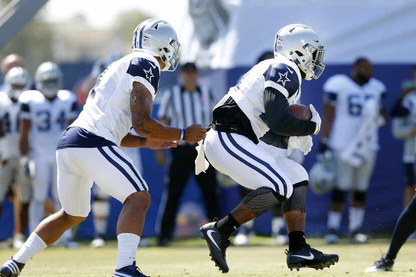 Dallas Cowboys running back Ezekiel Elliott (21, right) takes the handoff from quarterback...
