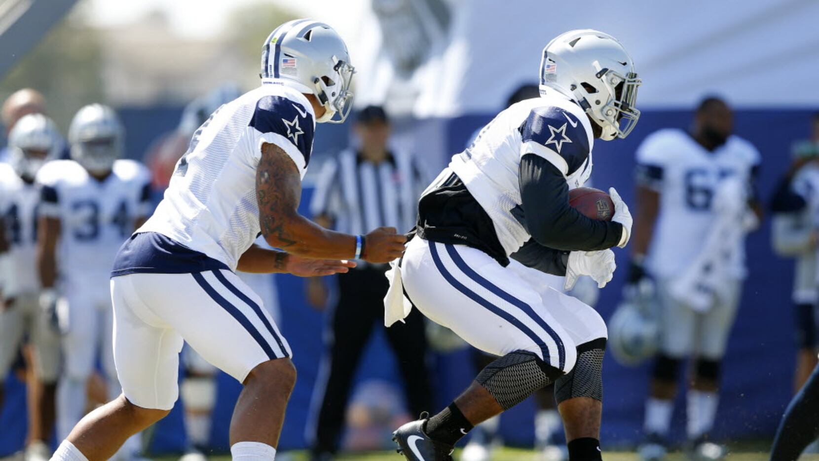 Dallas Cowboys running back Ezekiel Elliott (21, right) takes the handoff from quarterback...