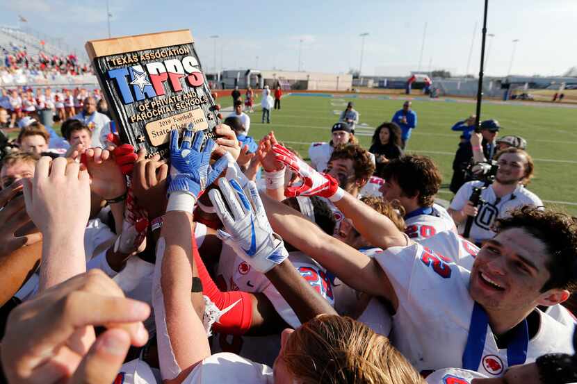 Parish Episcopal's football team hoists the trophy after receiving it during the awards...