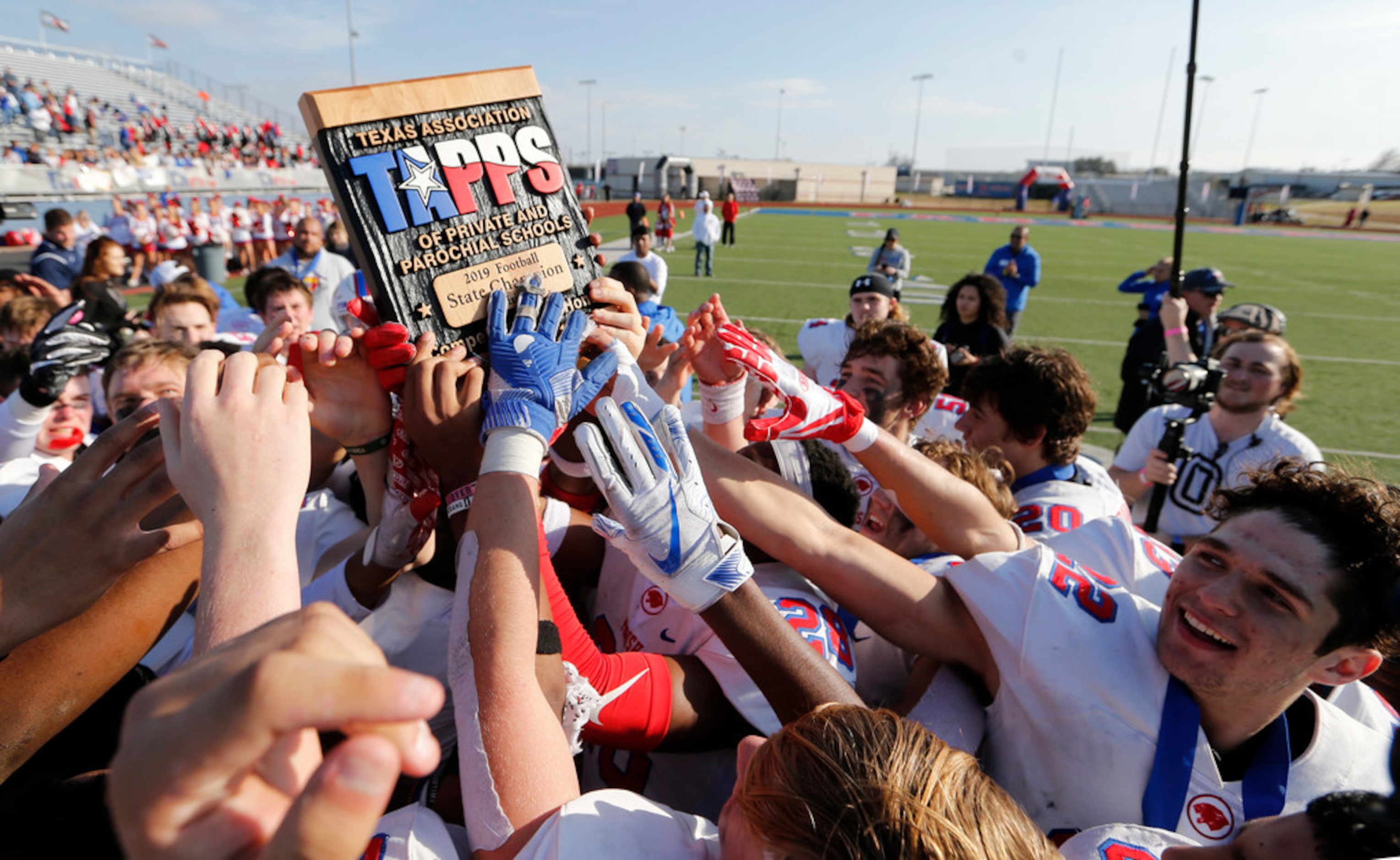 Parish Episcopal's football team hoists the trophy after receiving it during the awards...