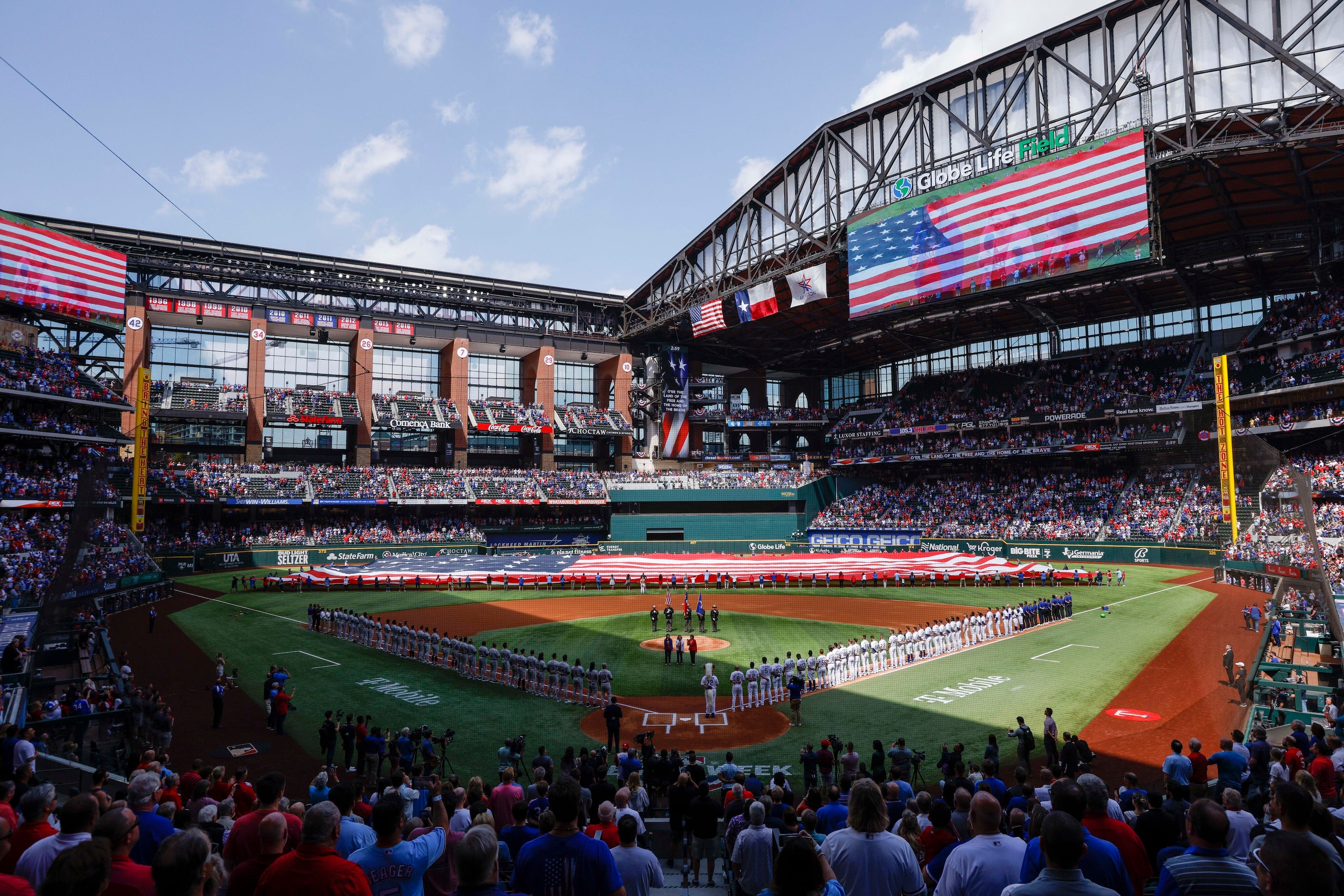 Fans and players stand for the national anthem before the Texas Rangers’ home opener against...