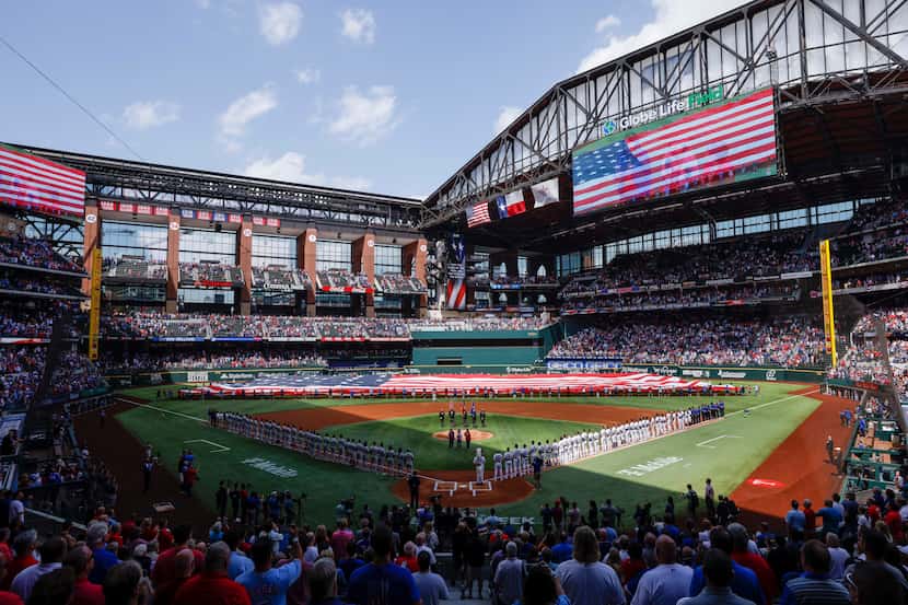 Fans and players stand for the national anthem before the Texas Rangers’ home opener against...