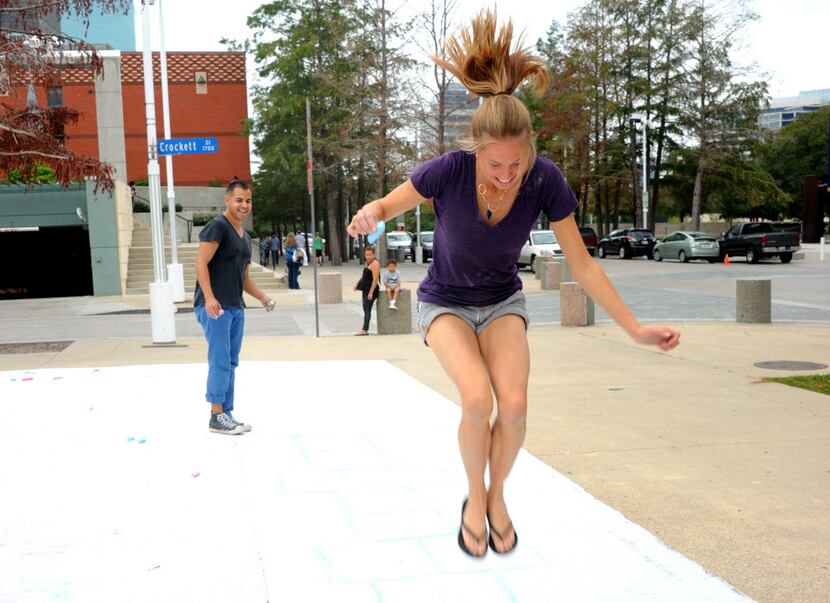 Amanda Popken and Patrick McDonnell, organizers of Chalk-tober Fest, play hopscotch across...