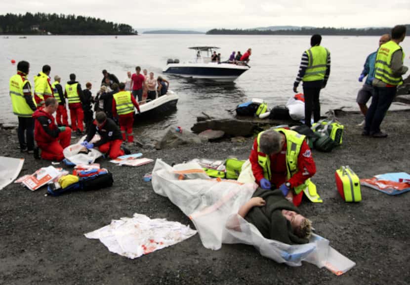 Emegency workers tend to victims on the lakeshore as a boat brings more wounded from Utaøya...