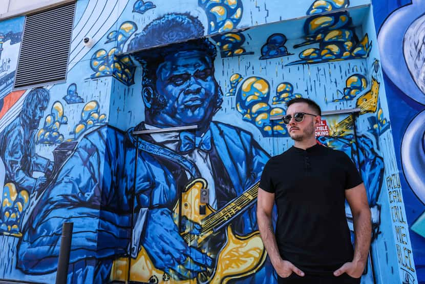 Alec DeJesus poses by his contribution to the alley, "The Texas Cannonball," which shows...