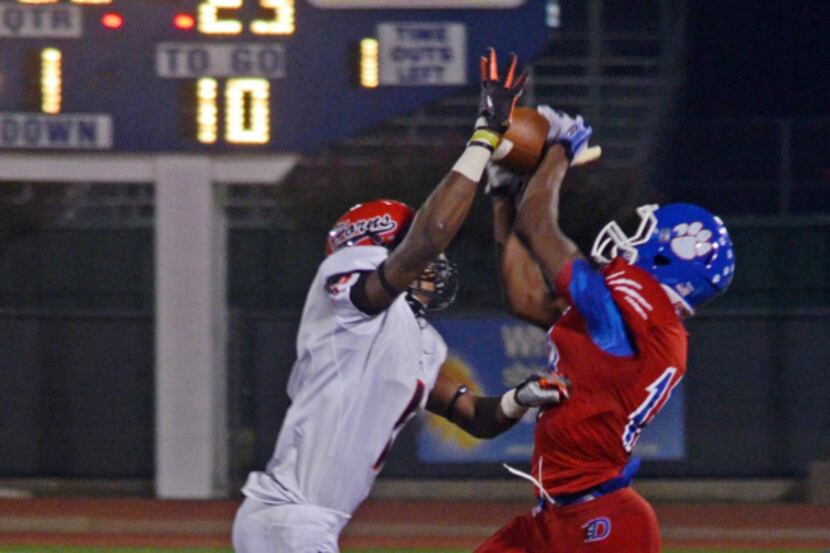 Duncanville senior running back Derrell Haynes (right) goes up for the pass above a Cedar...