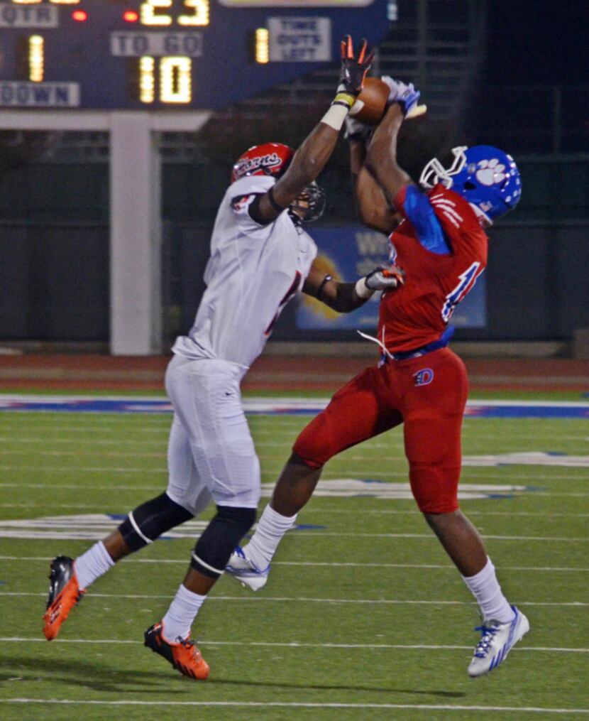 Duncanville senior running back Derrell Haynes (right) goes up for the pass above a Cedar...