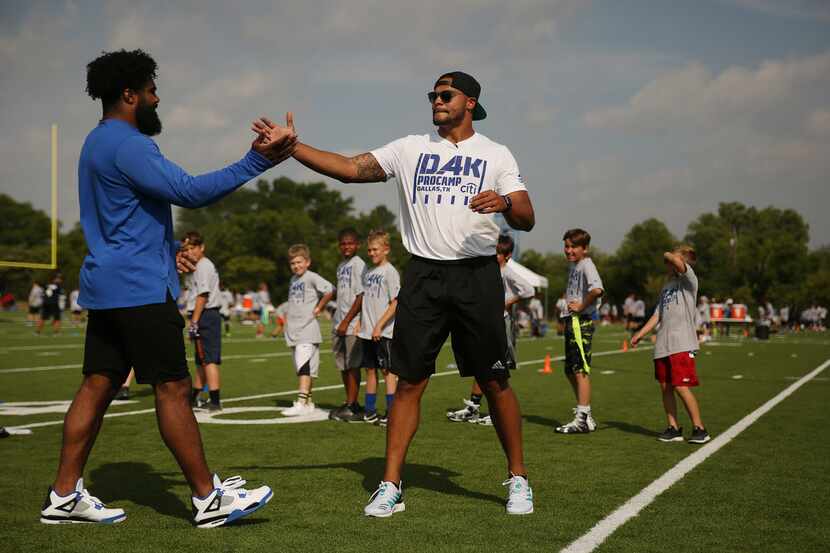 Dallas Cowboys quarterback Dak Prescott greets running back Ezekiel Elliott while...