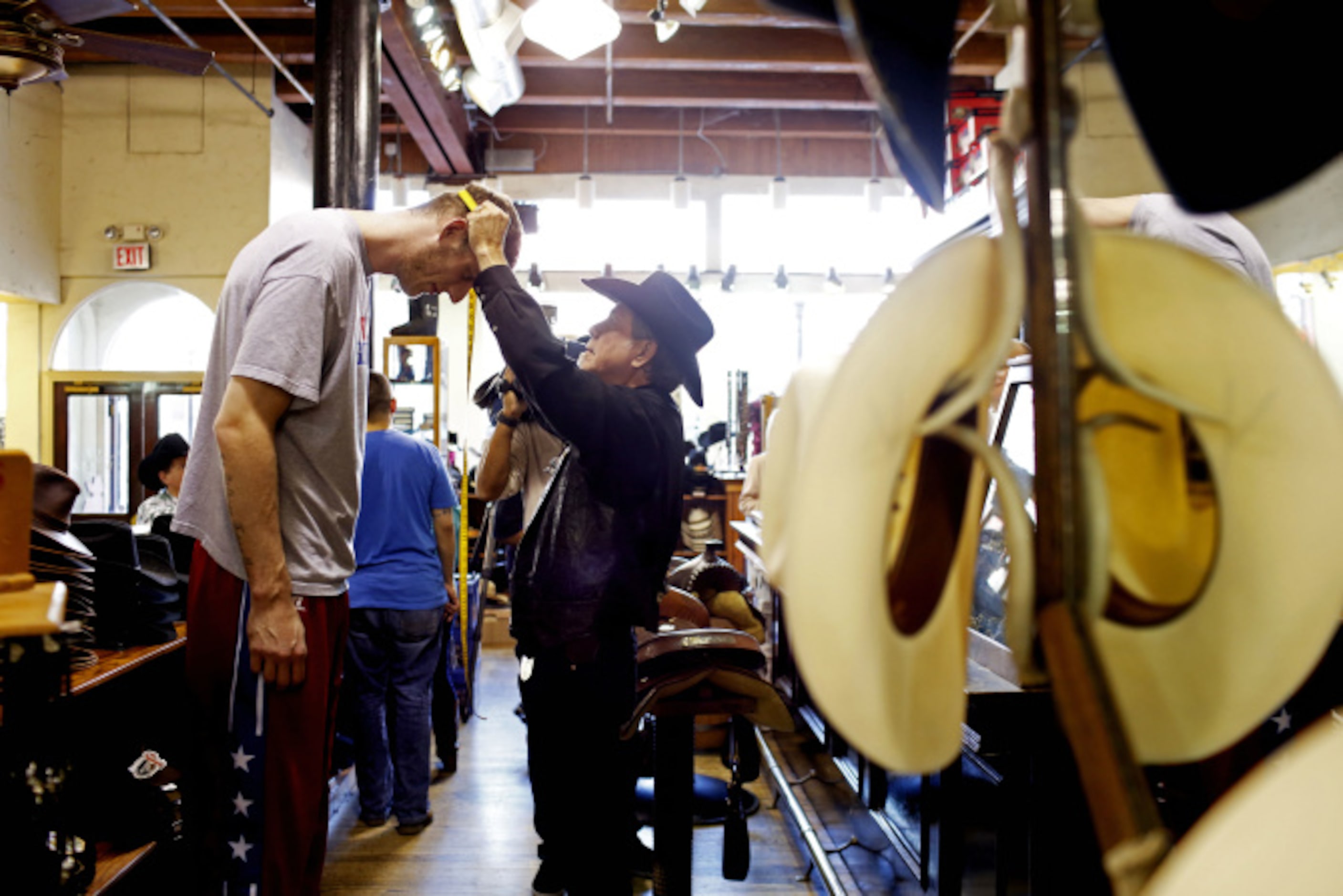 Bill Dewbre, owner of Wild Bill's Western Store, fits Paul "Tiny" Sturgess for a cowboy hat...