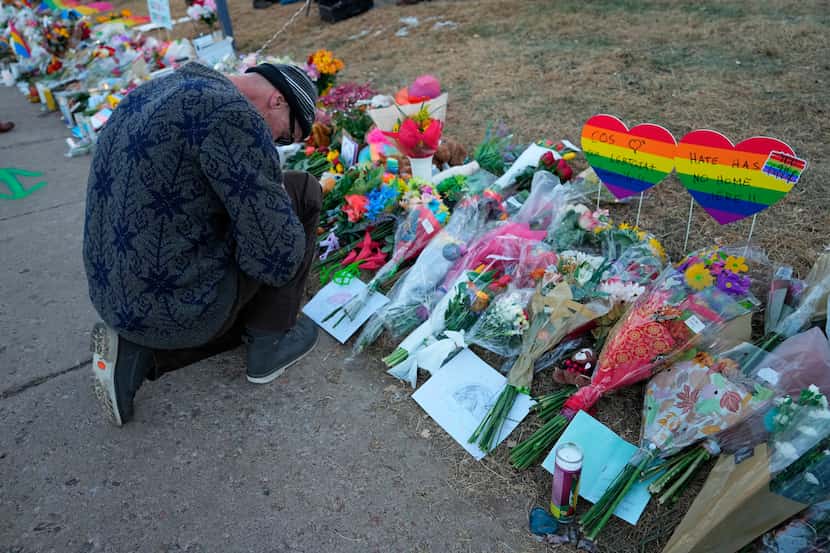 A man prays at a makeshift tribute with a display of bouquets of flowers on a corner near...