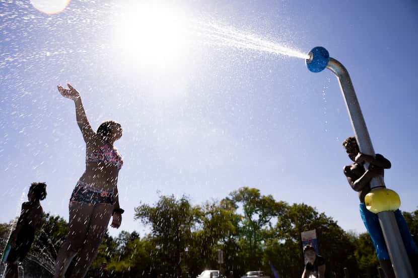 Brandon Burton, 8, (right) controls a water spray as children play at Danieldale Sprayground...