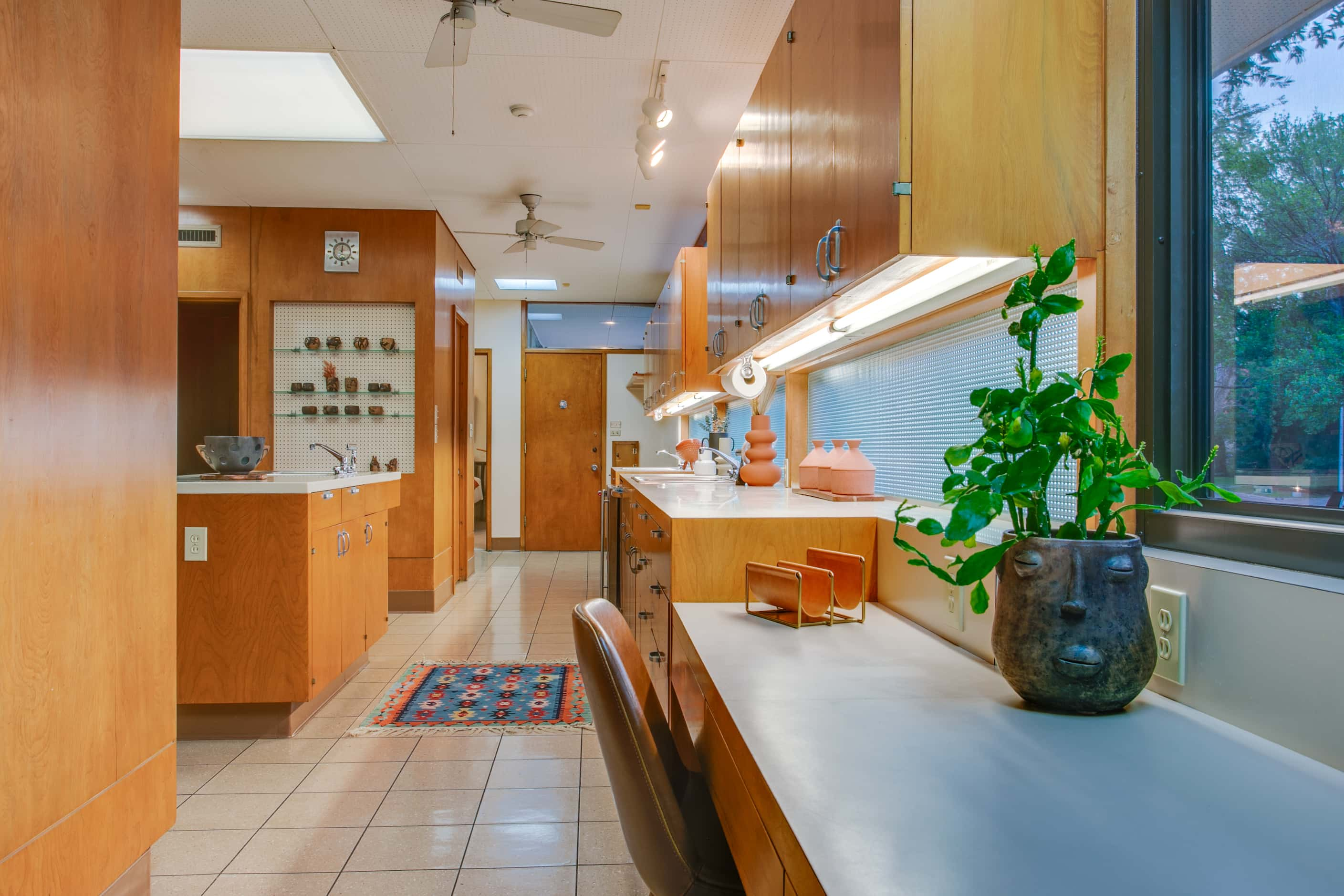 Midcentury kitchen with linoleum floors, wood cabinetry and engineered countertops