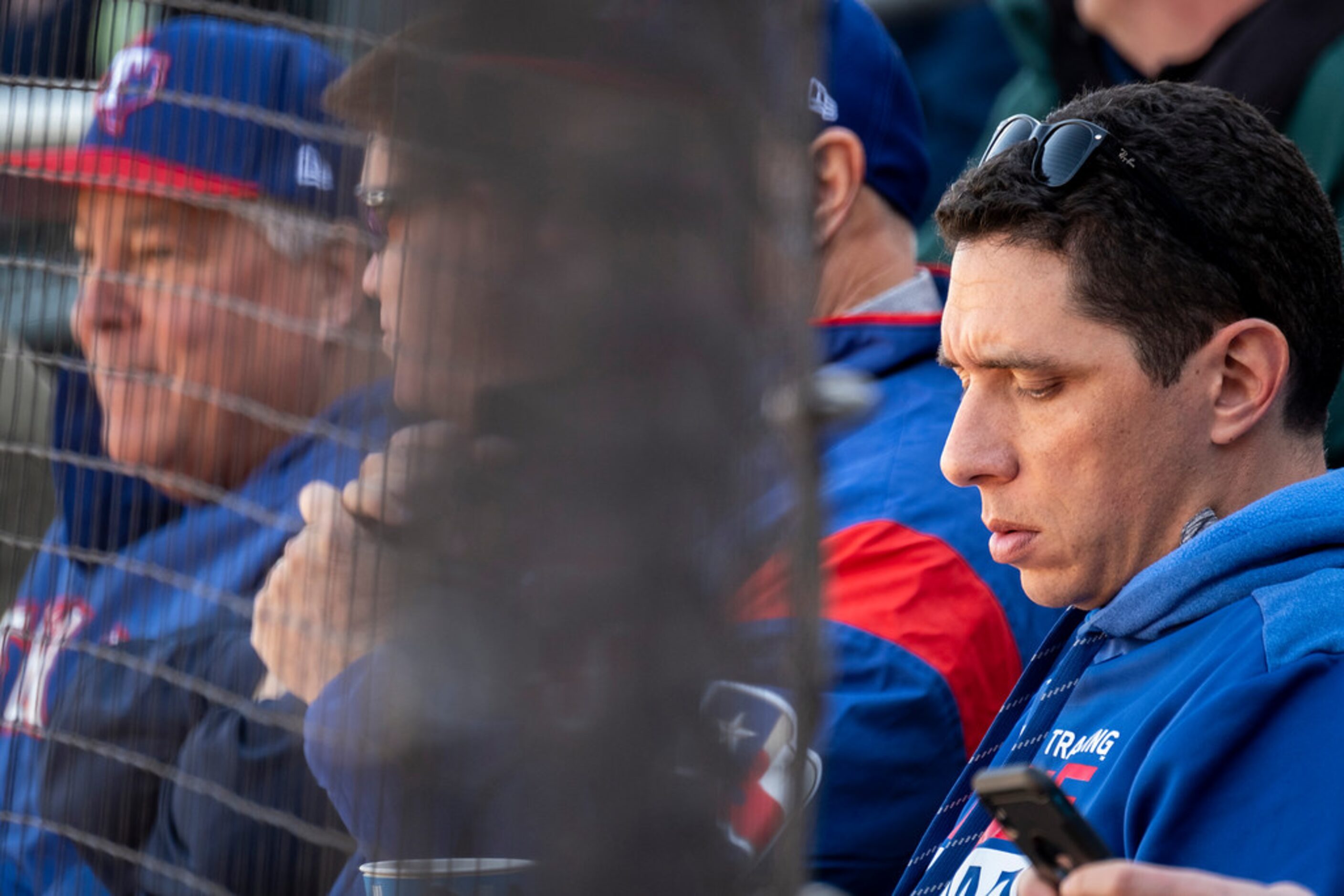 Texas Rangers general manager Jon Daniels checks his phone while watching a spring training...