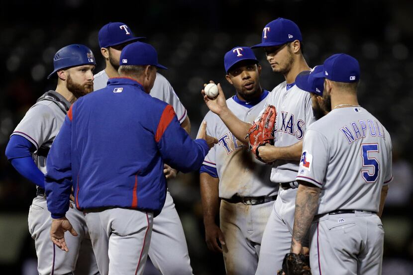 Texas Rangers pitcher Yu Darvish, second from right, hands the ball to manager Jeff Banister...