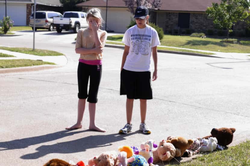 Two neighborhood girls looked at the stuffed animals left overnight near the spot where...