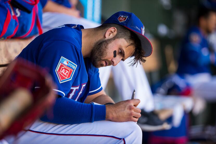 Texas Rangers infielder Joey Gallo writes in a notebook in the dugout during the sixth...