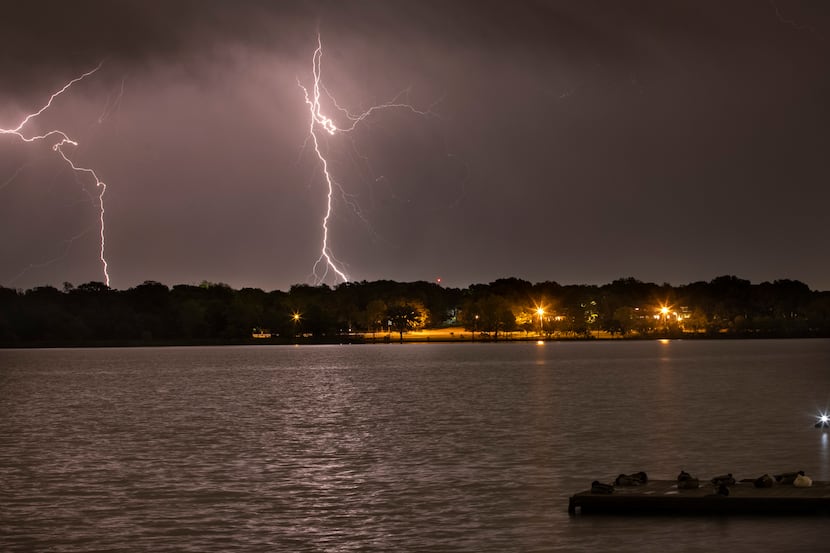 Ducks slumber beneath a lightning storm striking east of White Rock Lake in Dallas on Monday...
