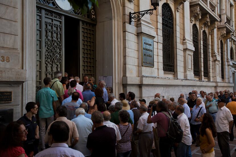 Pensioners wait outside the main gate of the national bank of Greece to withdraw a maximum...
