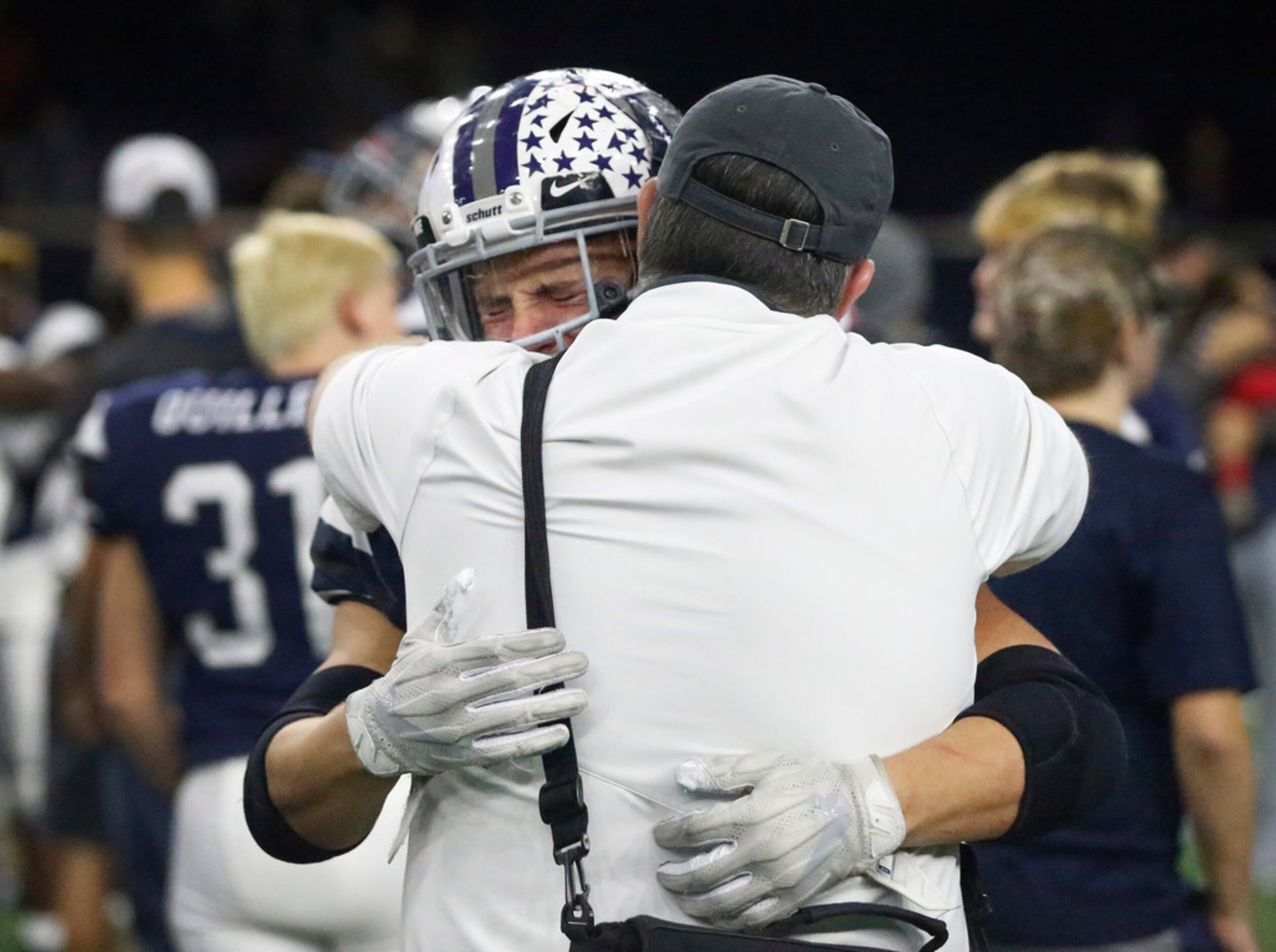 Richland High School's Rylee Johnson (20) is emotional as he embraces head coach Ged Kates...